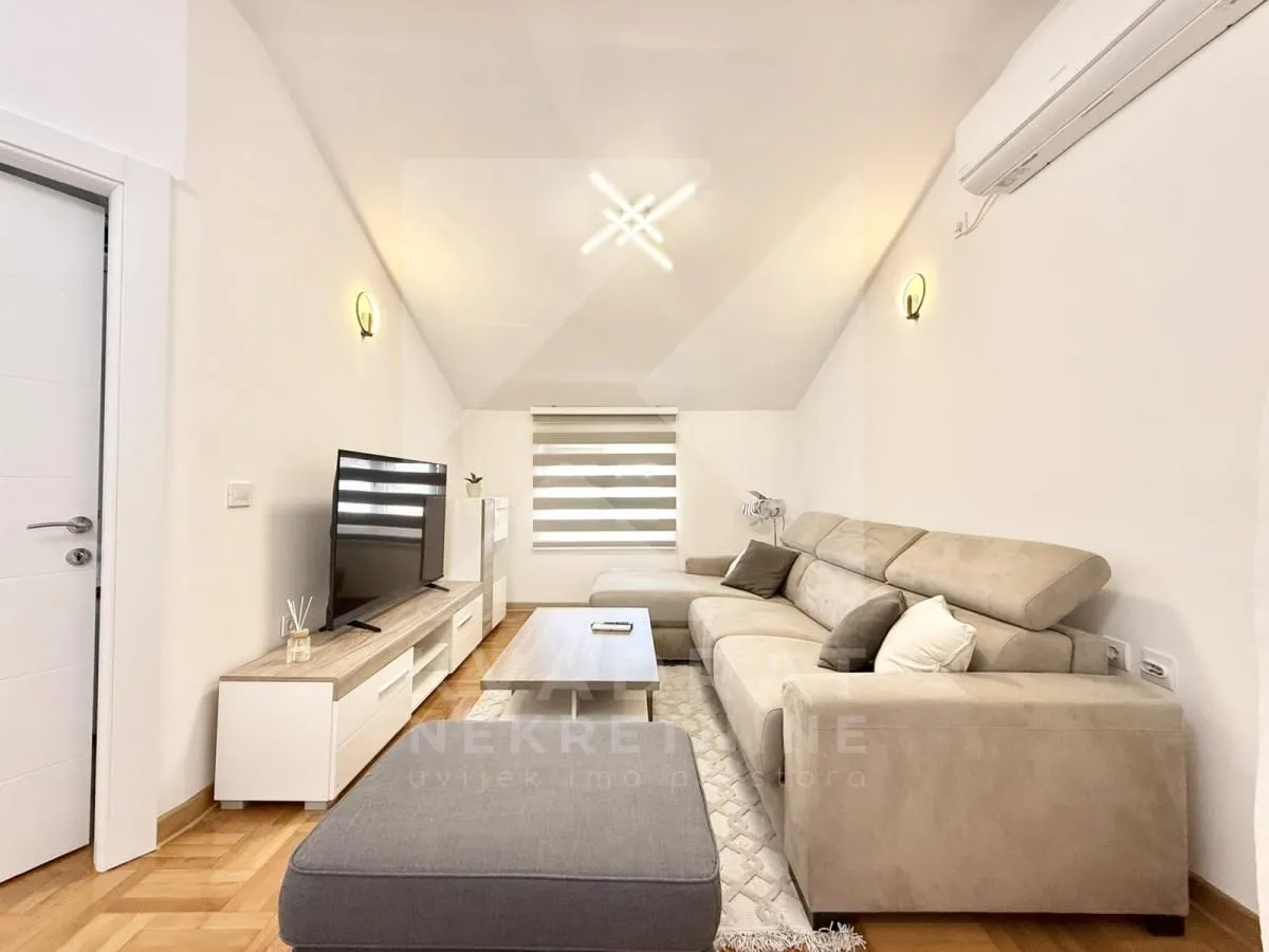 Comfortable living room with a sectional sofa, TV, and air conditioning.