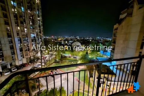 View from the balcony overlooking surrounding buildings and the city at night. - image 17