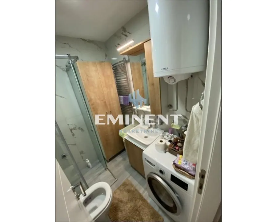 Equipped bathroom with a shower cabin, washbasin, and washing machine.