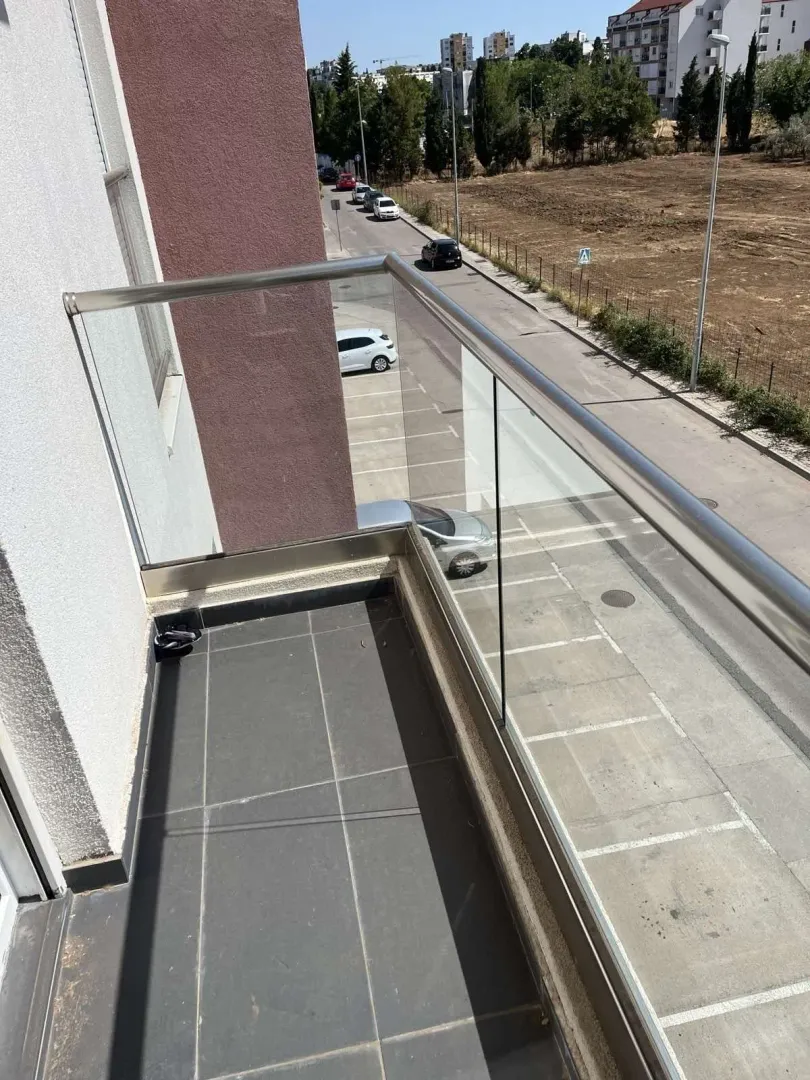 Balcony with a glass railing and street view.