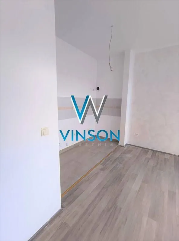 Prazna prostorija sa laminatom na podu i vidljivim instalacijama.