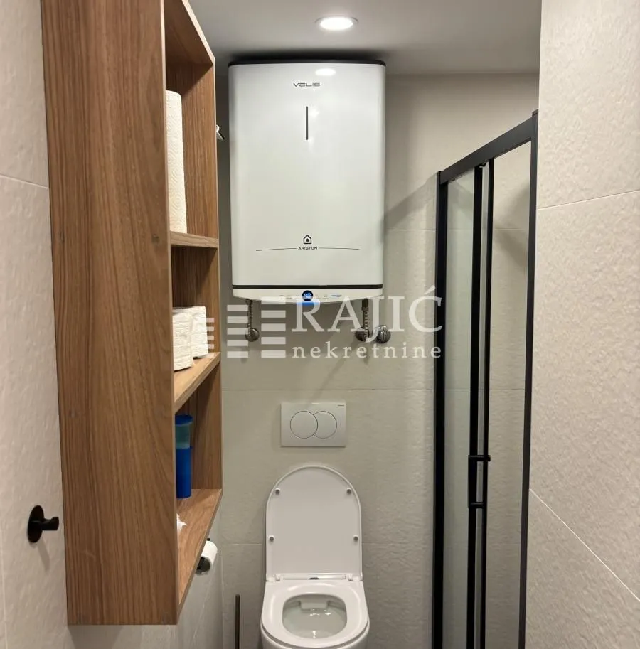 Small bathroom with a toilet, water heater and shower cabin.