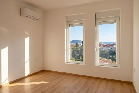 Empty room with wooden flooring, an air conditioner, and two windows with a view of the surroundings. - image 6