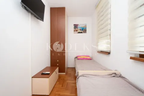 Smaller bedroom with two beds, a wardrobe, and a wall-mounted TV. - image 5