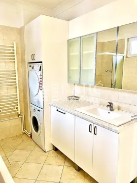 Compact bathroom with a sink, white cabinetry, and a stacked washer and dryer unit. - image 8