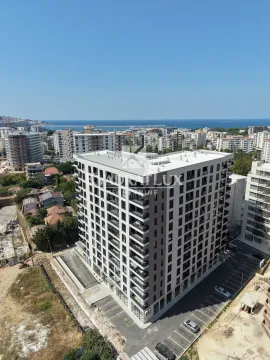 Aerial view of a modern residential building with the surrounding neighborhood and the sea in the background. - image 3