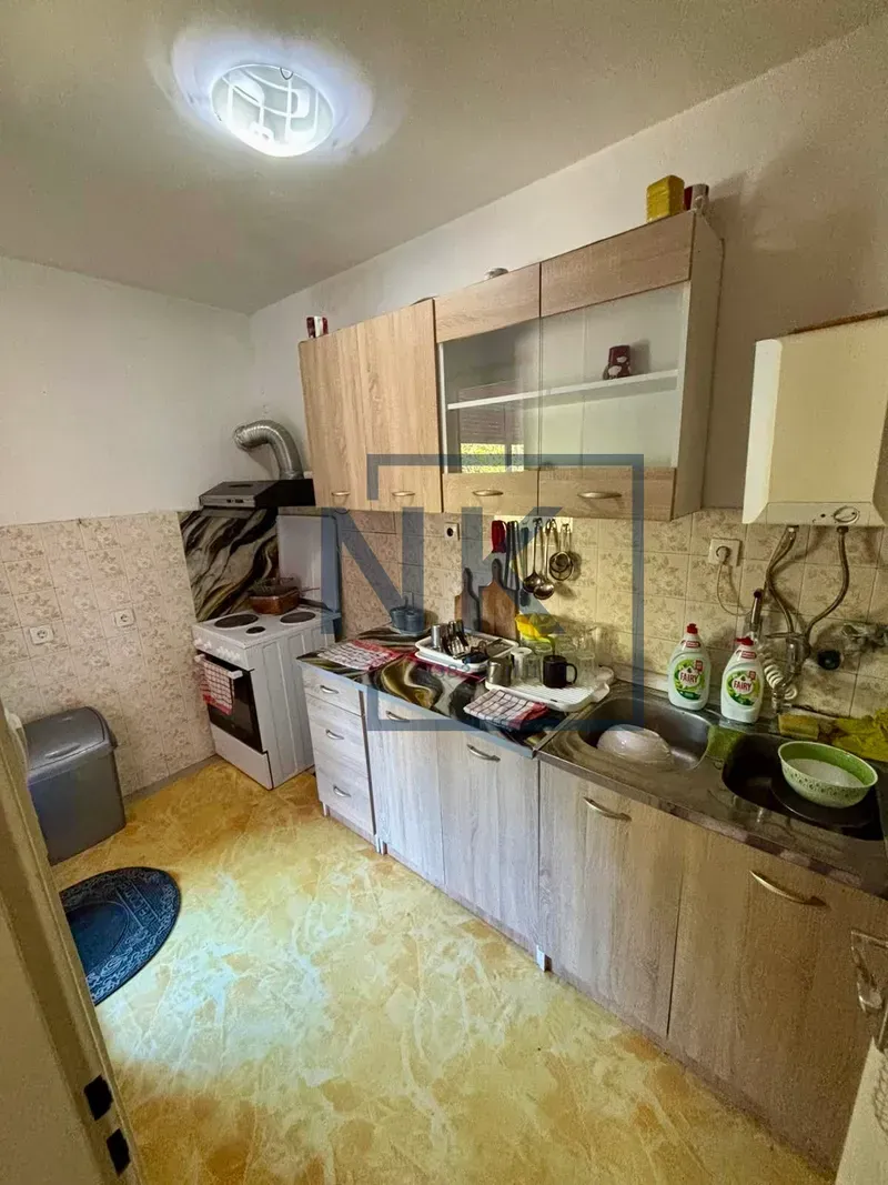 Manja kuhinja sa drvenim elementima, sudoperom i šporetom.