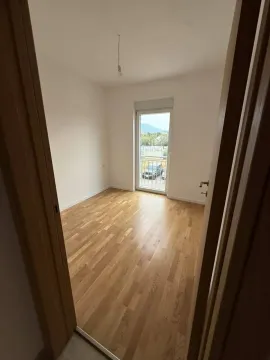Prazna soba sa parketom i vratima koja vode na terasu. - image 5
