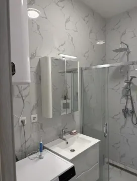 Moderne kupatilo sa tuš kabinom, umivaonikom i pločicama sa dezenom mermera. - image 15