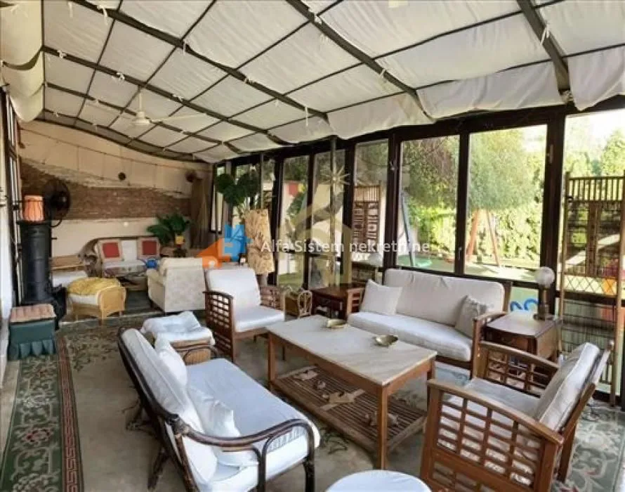 Enclosed terrace with seating furniture and a view of the yard.