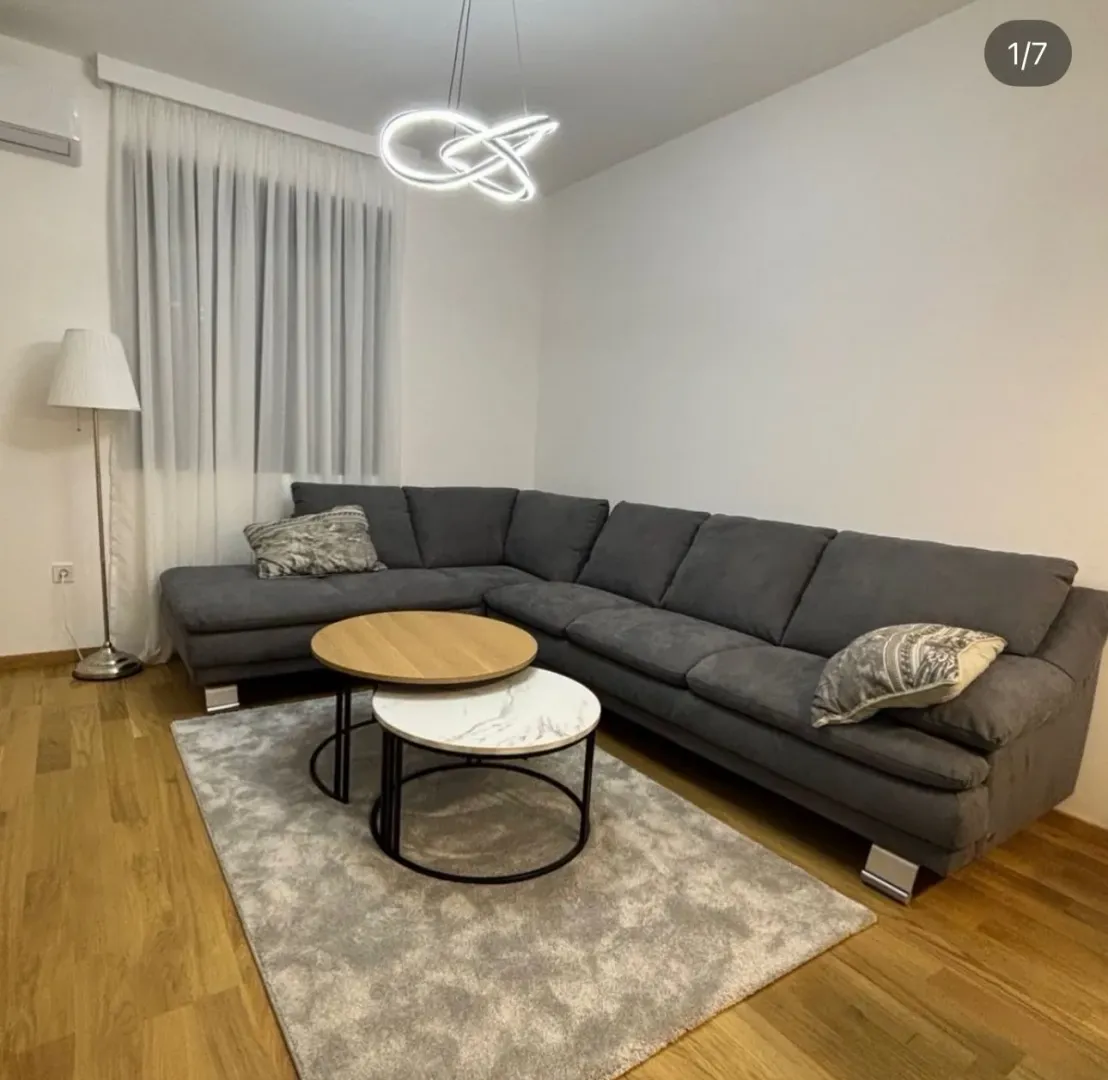 Dnevna soba sa ugaonom garniturom, stočićem i modernim osvjetljenjem.