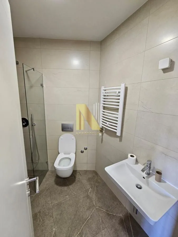 Moderno kupatilo sa tuš kabinom, umivaonikom i toaletom.