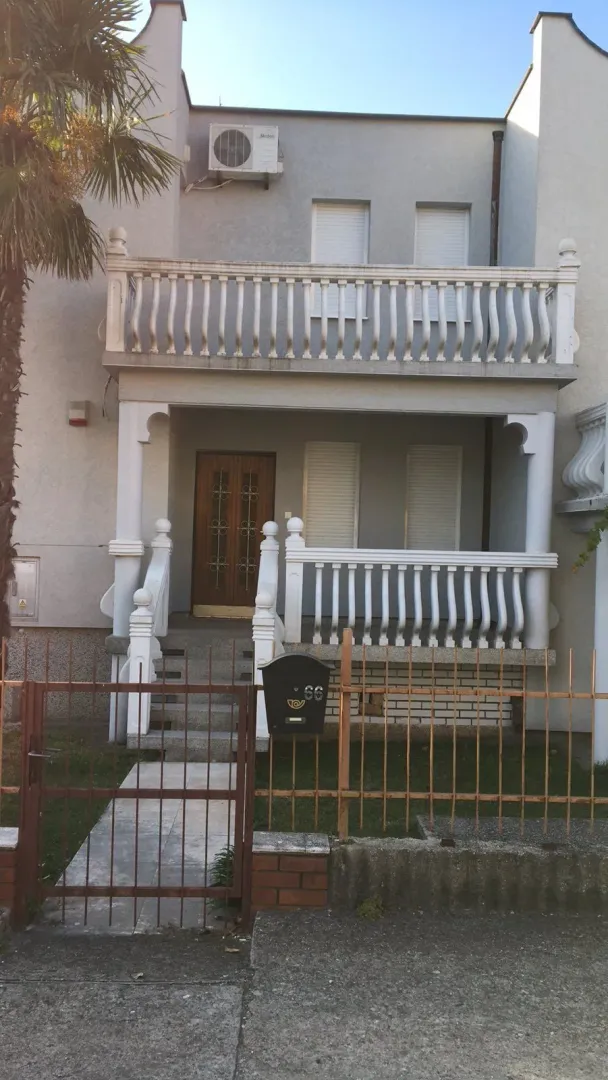 Exterior view of a two-story house with an entrance and balcony.