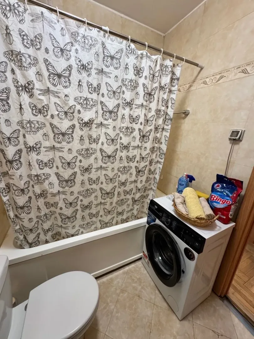 Manje uređeno kupatilo sa kadom, veš mašinom i toaletom.