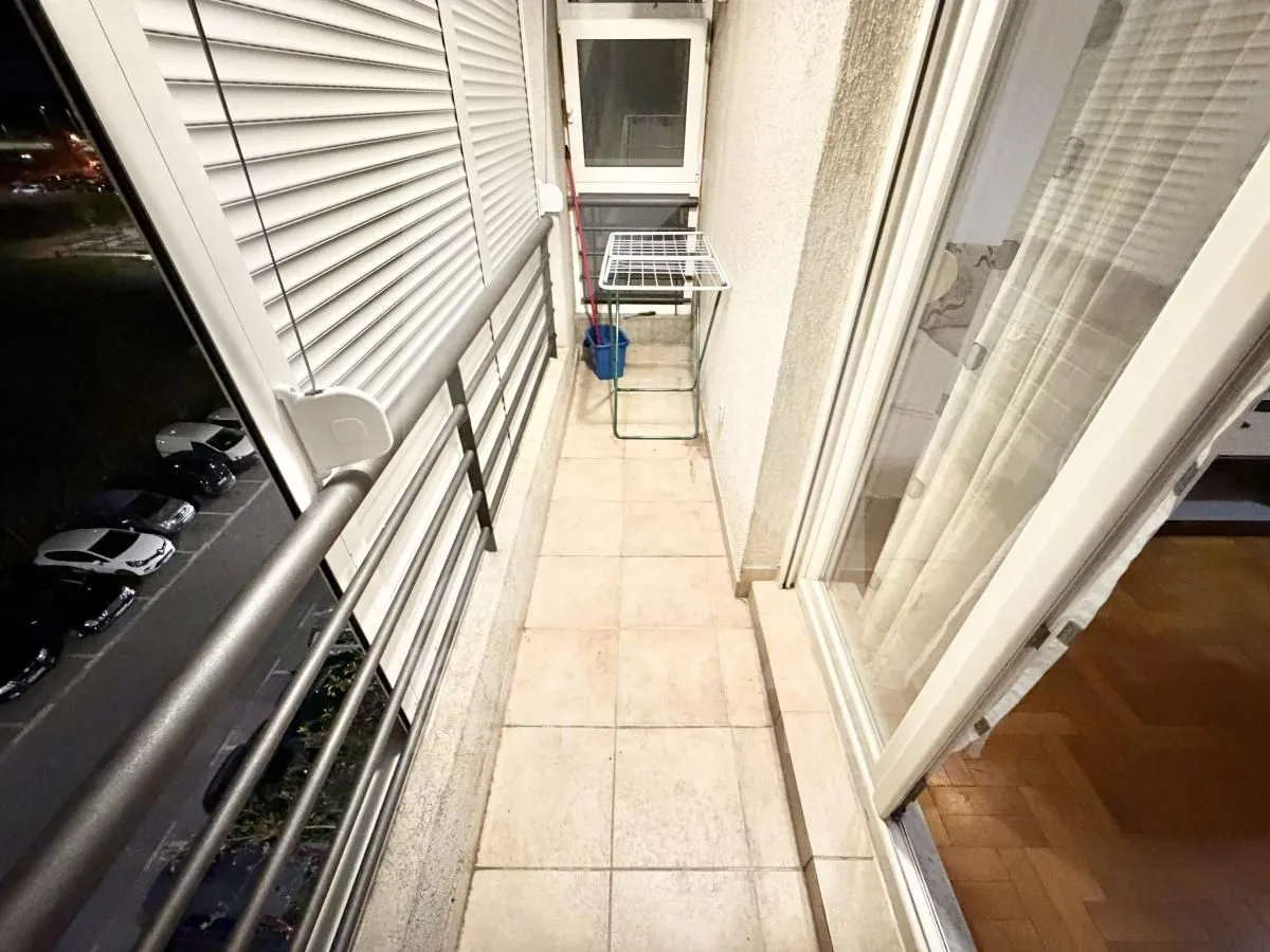 Uski balkon sa pločicama, ogradom i sušačem za veš.