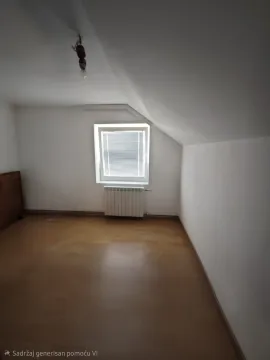 Prazna soba sa kosim plafonom, drvenim podom i prozorom. - image 18