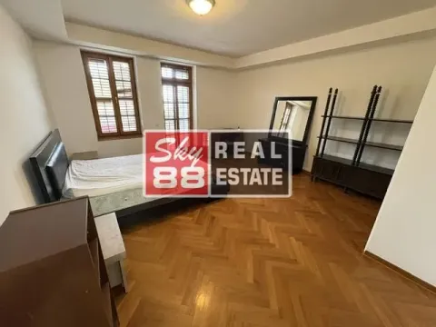Spacious bedroom with a double bed, wooden parquet flooring, and two windows. - image 15