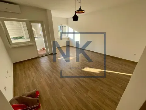 Empty room with wooden flooring, white walls, and balcony access. - image 5