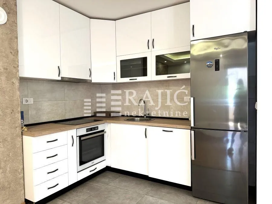 Modern kitchen with white cabinetry and built-in appliances.