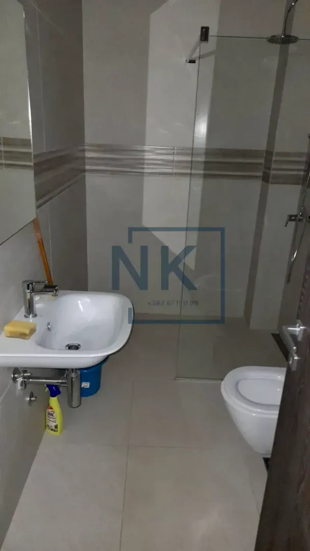 Kupatilo opremljeno umivaonikom, WC šoljom i tuš kabinom.