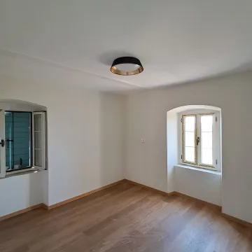 Empty room with wooden flooring, white walls, and two windows. - image 25