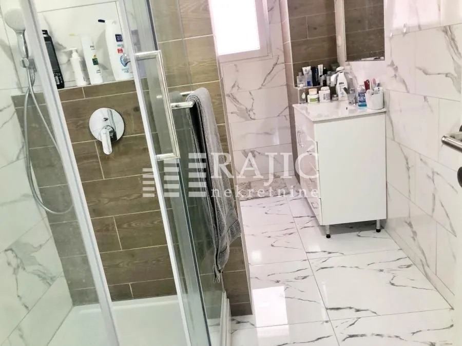 Modernly equipped bathroom with a shower cabin and sink.