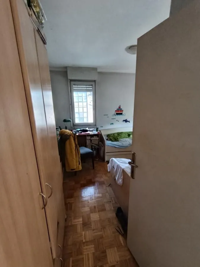 Pogled iz hodnika na nameštenu dečju sobu sa krevetom i ormarom.
