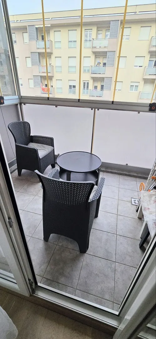 Enclosed balcony with seating furniture and a table.