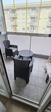 Enclosed balcony with seating furniture and a table. - image 9