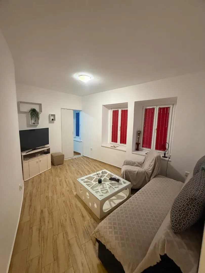 Dnevna soba sa garniturom, televizorom i stočićem.