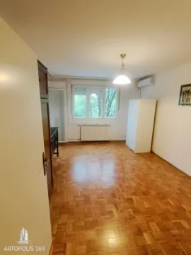 Prazna soba sa parketom, belim zidovima i prozorom koji gleda na zelenilo. - image 2