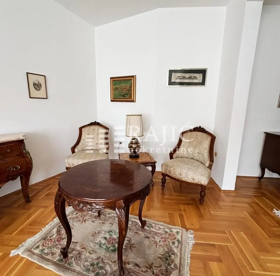 Living room with seating furniture and parquet flooring.