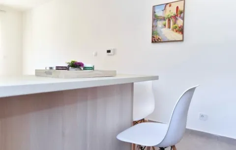 Modern kitchen with a counter and white chairs. - image 3