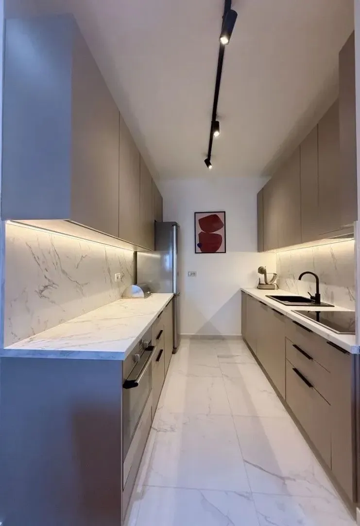 Modern and tidy kitchen with built-in cabinetry and marble countertops.