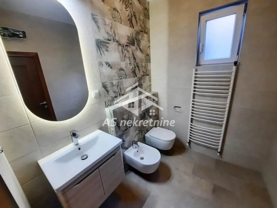 Moderno opremljeno kupatilo sa umivaonikom, WC šoljom, bideom i ogledalom.
