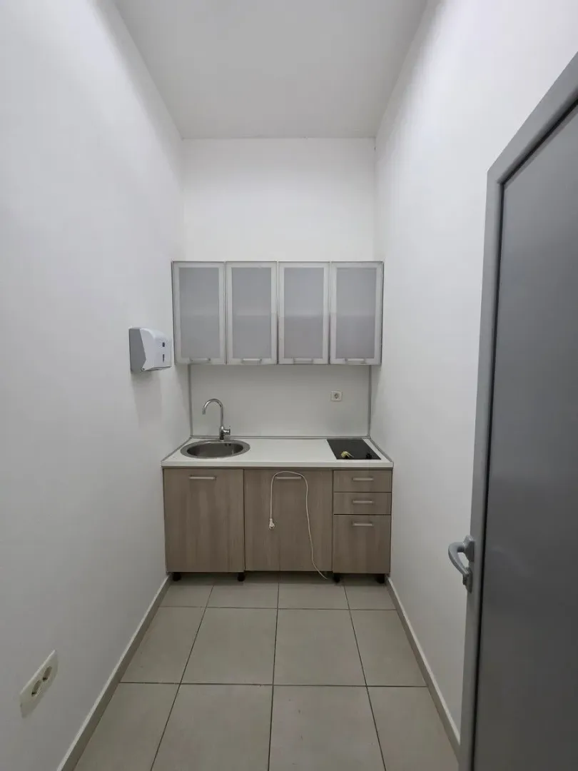 Small kitchenette in white and wood tones with a sink and countertop.