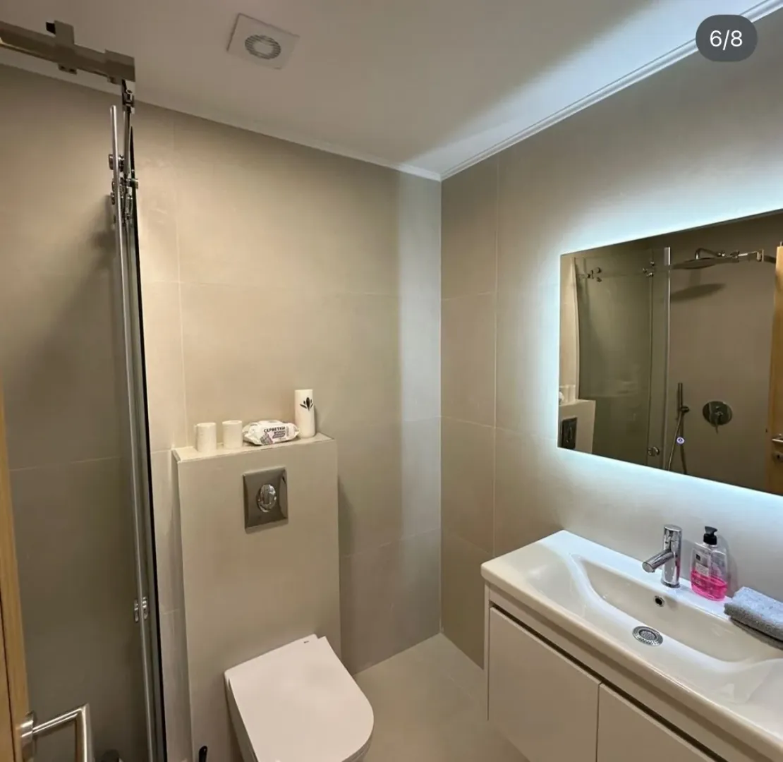 Modernly equipped bathroom with a shower cabin, washbasin, and toilet.