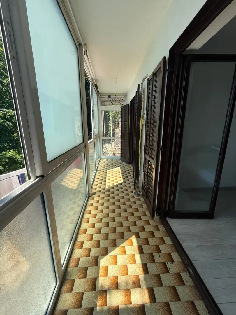 Zastakljeni balkon sa pločicama na podu i roletnama na prozorima.