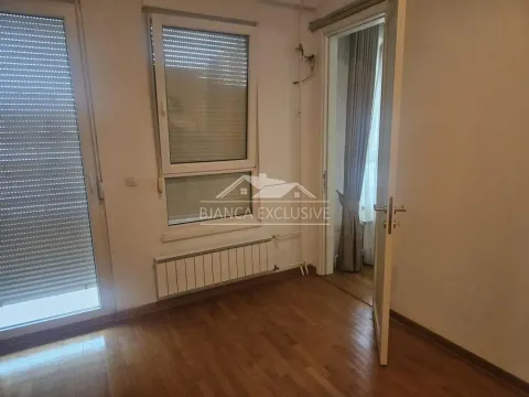 Prazna soba sa drvenim podom, prozorima sa roletnama i vratima koja vode u drugu prostoriju. - image 14