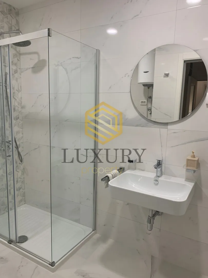 Modernly equipped bathroom with a shower cabin and sink.