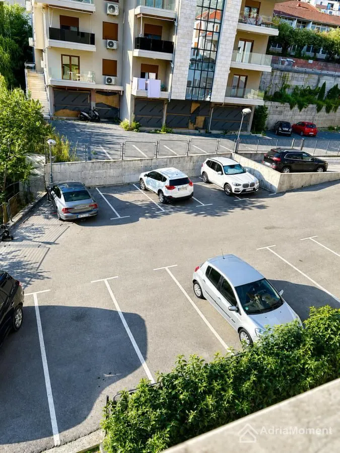 Pogled sa terase na parking ispred zgrade sa parkiranim automobilima.