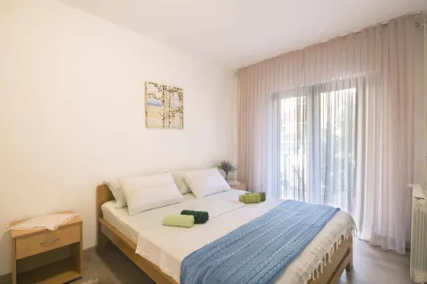 Spavaća soba sa bračnim krevetom, noćnim stočićima i velikim prozorom sa zavjesama. - image 23