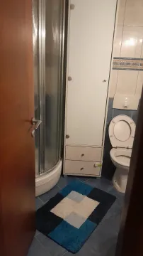 Kupatilo sa tuš kabinom, visokim bijelim ormarićem i toaletom. - image 10