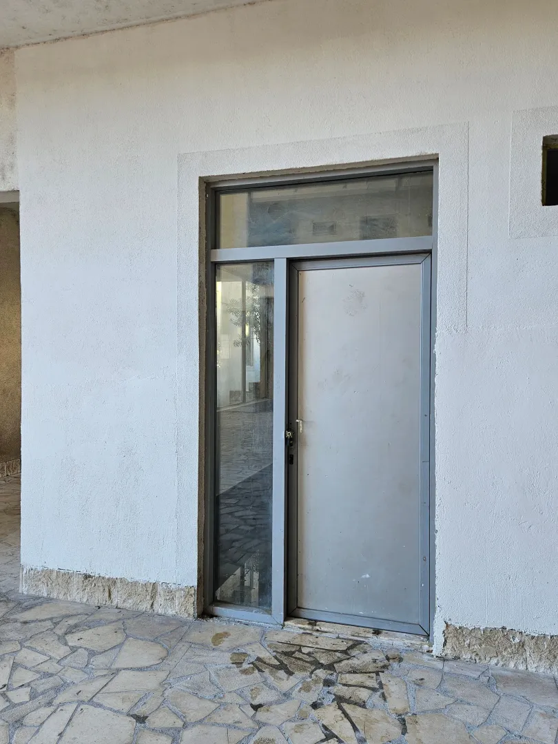 Entrance door of a commercial space or building with a white facade.