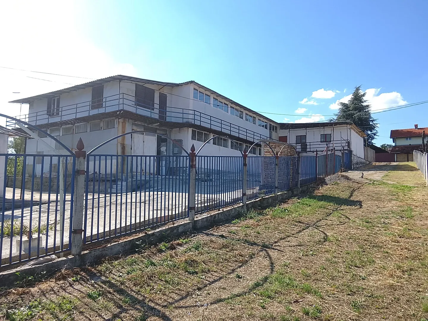 Exterior view of a commercial building with a yard and fence.