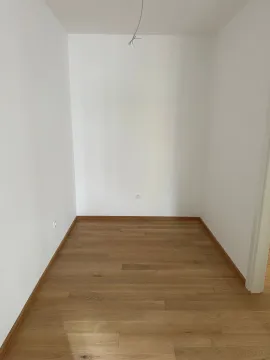 Empty room with white walls and wooden parquet flooring. - image 8
