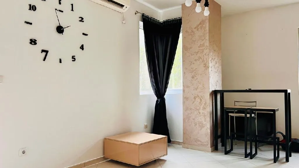 Living room with a modern wall clock and dining table.