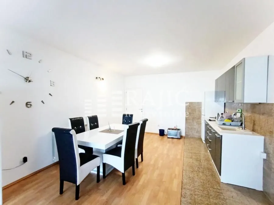 Modern kitchen with a dining area and white furniture.