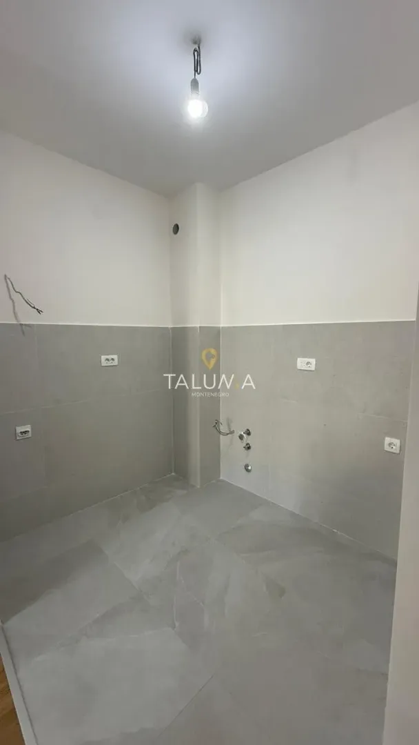Manja prostorija sa pločicama na donjem dijelu zidova i instalacijama.