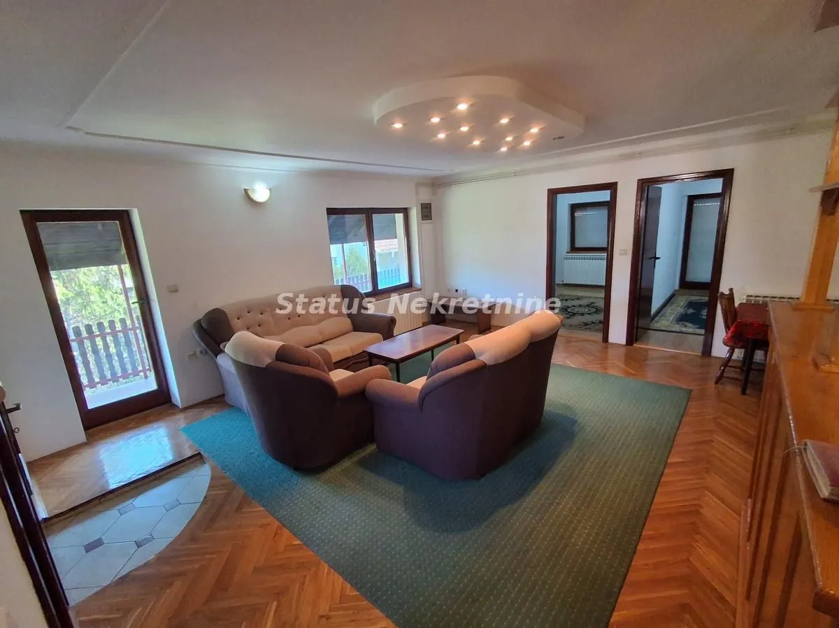 Spacious living room with seating furniture and parquet flooring.